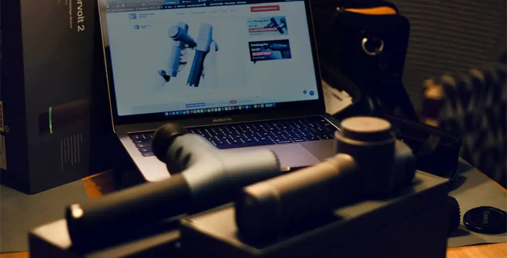 Our How to Choose a Massage Gun: Our Laptop on the background showing one of our review comparison of two different massage guns