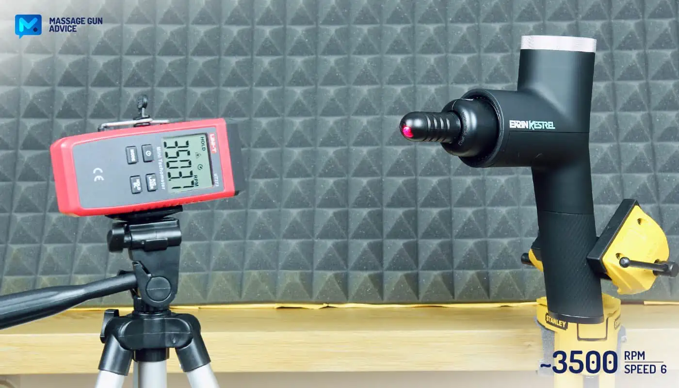 Ekrin Kestrel Review - Is This the Ultimate Massage Gun Unicorn? 32 Ekrin Kestrel clamped to a table while operating at its highest speed. Opposite to it, a digital tachometer on a tripod to measure RPMs